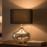 Verina table lamp. silver glass lamp. black linen shade. gourd style lamp. ambient lighting. modern table lamp. contemporary lighting. decorative lamp. bedside lamp. desk lamp. stylish lamp. compact lighting. luxury table lamp. silver finish. glass body lamp. round metal base. soft glow lamp. living room lighting. bedroom lighting. office lamp. minimalist lighting. transitional décor. home accessories. interior lighting. designer lamp.