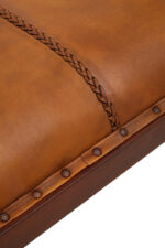 Cadenza Bench With Inverted Base. Tan leather bench. Teak wood base. Inverted V legs. Genuine leather upholstery. Nail head trim. Rustic modern bench. Luxury accent seating. Handcrafted furniture. Vintage-inspired design.