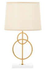Raya Gold Circles Table Lamp. Gold table lamp. White marble base lamp. Beige linen shade lamp. Art deco lighting. Modern gold lamp. Luxury table light. Elegant bedside lamp. Contemporary lighting design. Sculptural metal lamp. Living room lighting. Bedroom table lamp. Marble and gold décor. Boutique home accessory. Ambient light fixture. Minimalist table lamp. Designer home lighting. Statement lamp design. Modern art deco décor.