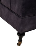 Naya Velvet Ottoman. Dark grey velvet ottoman. Velvet footstool. Tufted velvet ottoman. Chesterfield style ottoman. Luxury ottoman seat. Modern velvet furniture. Grey velvet footrest. Living room ottoman. Plush velvet accent. Castor wheel ottoman. Padded velvet stool. Elegant grey ottoman. Contemporary velvet décor.