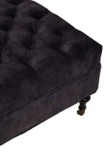 Naya Velvet Ottoman. Dark grey velvet ottoman. Velvet footstool. Tufted velvet ottoman. Chesterfield style ottoman. Luxury ottoman seat. Modern velvet furniture. Grey velvet footrest. Living room ottoman. Plush velvet accent. Castor wheel ottoman. Padded velvet stool. Elegant grey ottoman. Contemporary velvet décor.