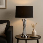 Hudson Twisted Base Table Lamp. Nickel finish lamp. Stainless steel table lamp. Black shade lamp. Modern metallic lighting. Luxury home décor lamp. Sculptural twisted base. Hourglass table lamp. Contemporary bedside lamp. Designer accent lighting. Elegant living room light. Monochrome home accessory. Reflective silver lamp. Boutique style lighting.