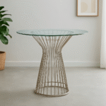 Kaya Glass Dining Table. Round glass dining table. Silver stainless steel base. Modern dining furniture. Art deco dining table. Luxury dining room design. Contemporary glass table. Geometric metal base table. Sleek modern dining set. Reflective silver furniture. Boutique home décor. Minimalist dining table. Clear glass tabletop. Modern round table. Durable stainless steel frame. Elegant dining furniture. Stylish home interiors. Opulent dining design. Statement dining table. Timeless modern décor.