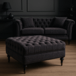 Naya Velvet Ottoman. Dark grey velvet ottoman. Velvet footstool. Tufted velvet ottoman. Chesterfield style ottoman. Luxury ottoman seat. Modern velvet furniture. Grey velvet footrest. Living room ottoman. Plush velvet accent. Castor wheel ottoman. Padded velvet stool. Elegant grey ottoman. Contemporary velvet décor.