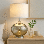 Perrin Ball Shaped Table Lamp. Glass base lamp. Metallic finish lamp. Chrome table lamp. Modern bedside lighting. Contemporary home décor. Elegant living room lamp. White fabric shade. Minimalist glass lighting. Designer accent lamp. Reflective glass lamp. Soft ambient light. Boutique style lamp. Classic meets modern lighting.