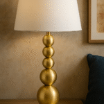 Rae Stacked Table Lamp. Brass table lamp. Orb base lamp. Modern lighting. Luxe home décor. Boutique-style lamp. White linen shade. Contemporary bedside light. Sculptural design lamp. Gold Table Lamp.